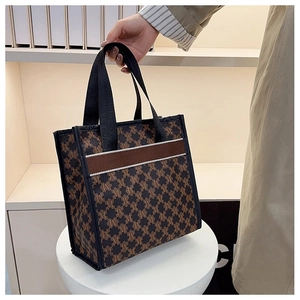 Close-up of brown jacquard tote bag featuring letter M pattern and leather trim