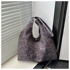 Macro shot of stylish leopard print hobo tote bag with oversized silver metal grommets