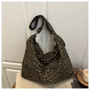 Detail of adjustable black shoulder strap on leopard print canvas crossbody tote bag