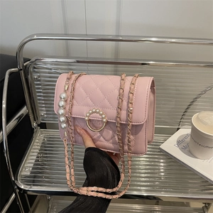 Pink quilted chain crossbody bag with pearl ring buckle and pearl charm on a chair