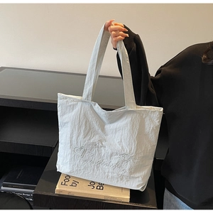 Détail de broderie de cœur et d'étoile sur un sac cabas en tissu gaufré