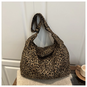 Detail shot of leopard print canvas tote bag with adjustable wide strap on soft knitwear