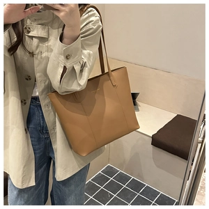 Close-up of caramel faux leather tote bag with gold logo and long shoulder strap