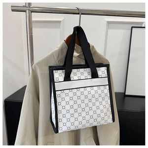 Close-up of printed tote bag with black geometric pattern on white canvas and black handles