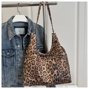 Detail of leopard print tote bag with wide shoulder strap hanging on a metal rack