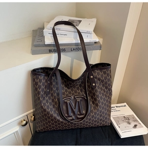 Détail du sac cabas marron foncé avec logo M en relief et imprimé monogramme élégant