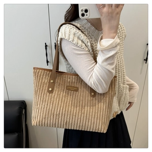Detail van bruine corduroy tote bag met geribbelde textuur en lederen schouderriem