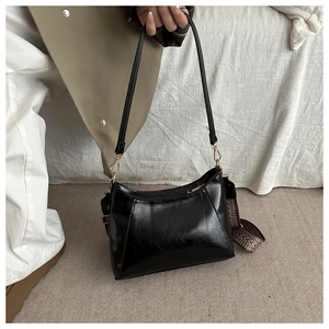 Détail du sac cabas noir brillant avec fermeture éclair dorée et bandoulière rayée