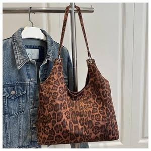 Detail of leopard print tote bag with silver eyelets hanging on a chrome rack