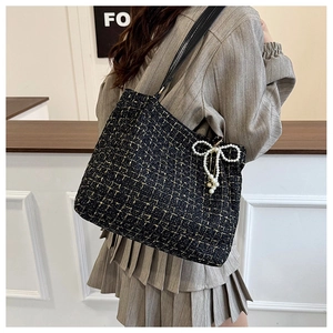Detail der Tweed-Schultertasche mit Goldfaden und dekorativem Perlen-Bogen-Anhänger