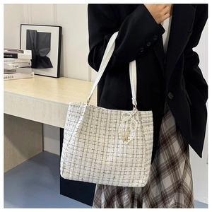 Détail du sac cabas en tweed blanc cassé avec coutures dorées et breloque perle