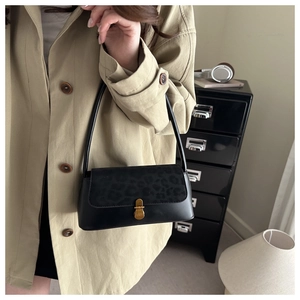 Close-up of leopard print flap detail and gold metal lock on black leather handbag