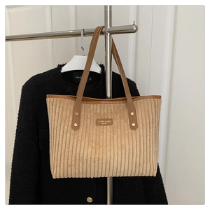 Detail van corduroy tote bag met lederen handvatten en metalen klinknagels