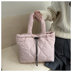 Detailed view of pink heart-quilted tote bag featuring polka dot drawstring and soft handle
