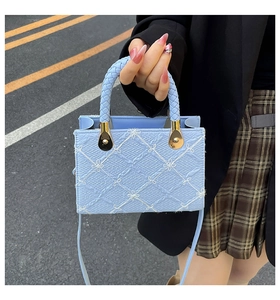 Detailed macro view of light blue embossed square bag with white floral embroidery