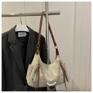 Detail of grey marbled shoulder bag with brown leather strap and pearl chain accent