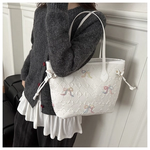 Detailed close-up of white quilted tote bag with colorful decorative ribbons and bows