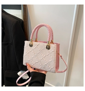 Close-up of pink and white crossbody bag with 3D diamond texture and woven handle