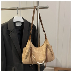 Detail of vintage camel suede handbag featuring double zippers and pearl chain decoration