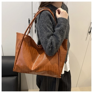 Close-up of the brown tote bag featuring detailed crocodile texture and long shoulder straps
