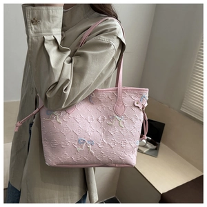 Close-up of pink quilted tote bag featuring colorful embroidered bows and side drawstring