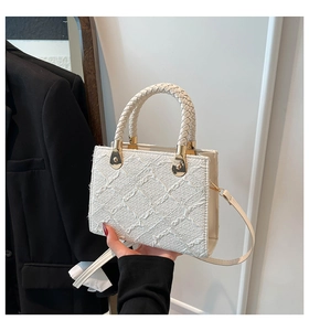 Detail of white woven textured handbag with gold metal hardware and stylish handle