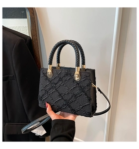 Close-up of black quilted handbag with woven handle and gold metal hardware detail