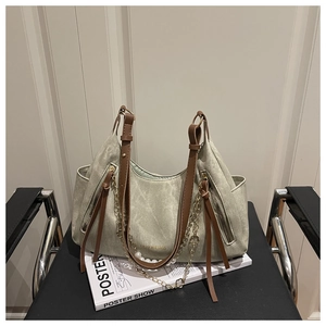 Detail of green tote bag with brown leather straps and gold chain featuring white pearls