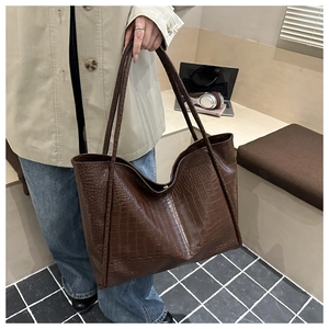 Detail of dark brown tote bag showing crocodile texture and spacious compartment