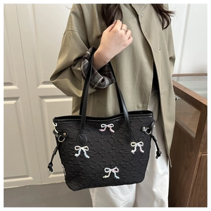 Close-up of black quilted tote bag with colorful bead bow motifs and textured fabric
