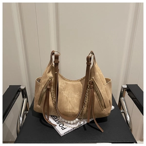 Detail of tan suede shoulder bag featuring long fringe zippers and pearl chain decor