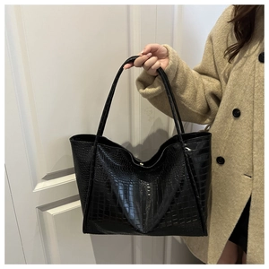 Close-up of black crocodile pattern leather tote bag with long shoulder straps