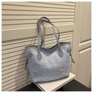 Detail showing light blue quilted tote with colorful embroidered bows and side tassels