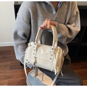 Gros plan d'un sac à main en similicuir beige avec rivets argentés et franges