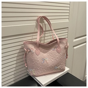 Detail of pink textured leather tote bag featuring colorful bow accents and side drawstrings