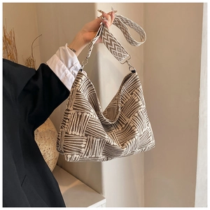 Close-up of woven canvas tote bag with brown geometric pattern and wide shoulder strap