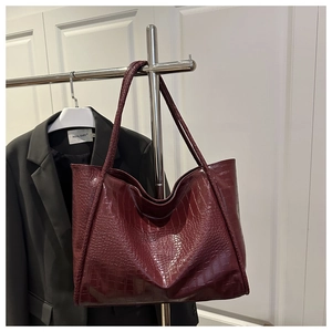 Close-up of wine red crocodile embossed leather texture on a large capacity tote bag