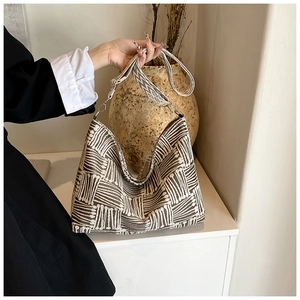 Detail of embroidered geometric pattern and wide jacquard strap on a canvas tote bag
