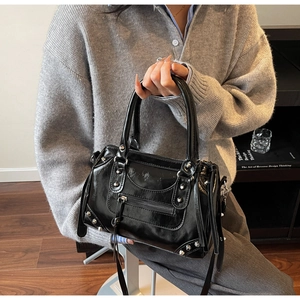 Détail d'un sac Boston noir brillant avec des clous argentés et des finitions à franges