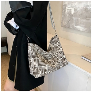 Close-up of geometric woven tote bag with silver hardware and grey shoulder strap