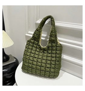 Close-up of green puffy quilted shoulder bag with soft padded texture and unique bubble design
