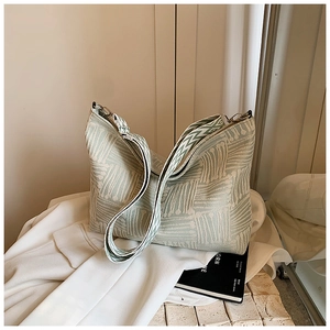 Detail of light green geometric jacquard tote bag leaning on a white casual blazer