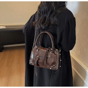 Vue détaillée du sac Boston marron foncé avec des clous argentés et un gland sur modèle