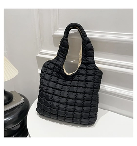 Detail of black quilted tote bag featuring a textured bubble pattern and light beige lining