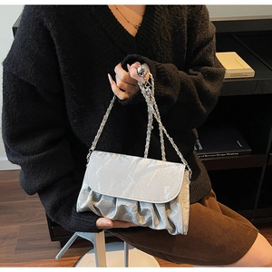 Silver pleated metal texture crossbody bag shown being carried in a luxury setting