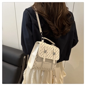 Chic cream-colored backpack with black polka dots and Tidal Dryness text on a model