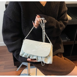 Detail of white pleated handbag with silver woven chain strap and round crystal charm