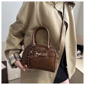 Detail of brown vintage crossbody bag with decorative metallic buckle and woven strap