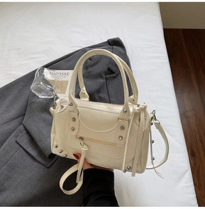Détails du sac Boston crème avec rivets métalliques et doubles poignées texturées