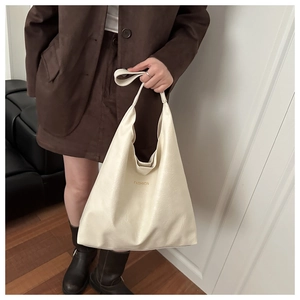 Detail of cream white faux leather handbag with FASHION text and minimalist handle design